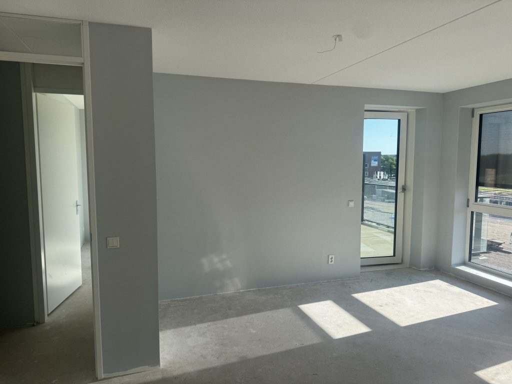 Appartement in afwerking met een lichtgrijze wand en een betonvloer