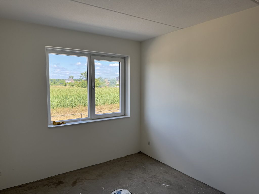 Lege kamer met kale, gladde wanden en een raam, klaar voor nieuw behang